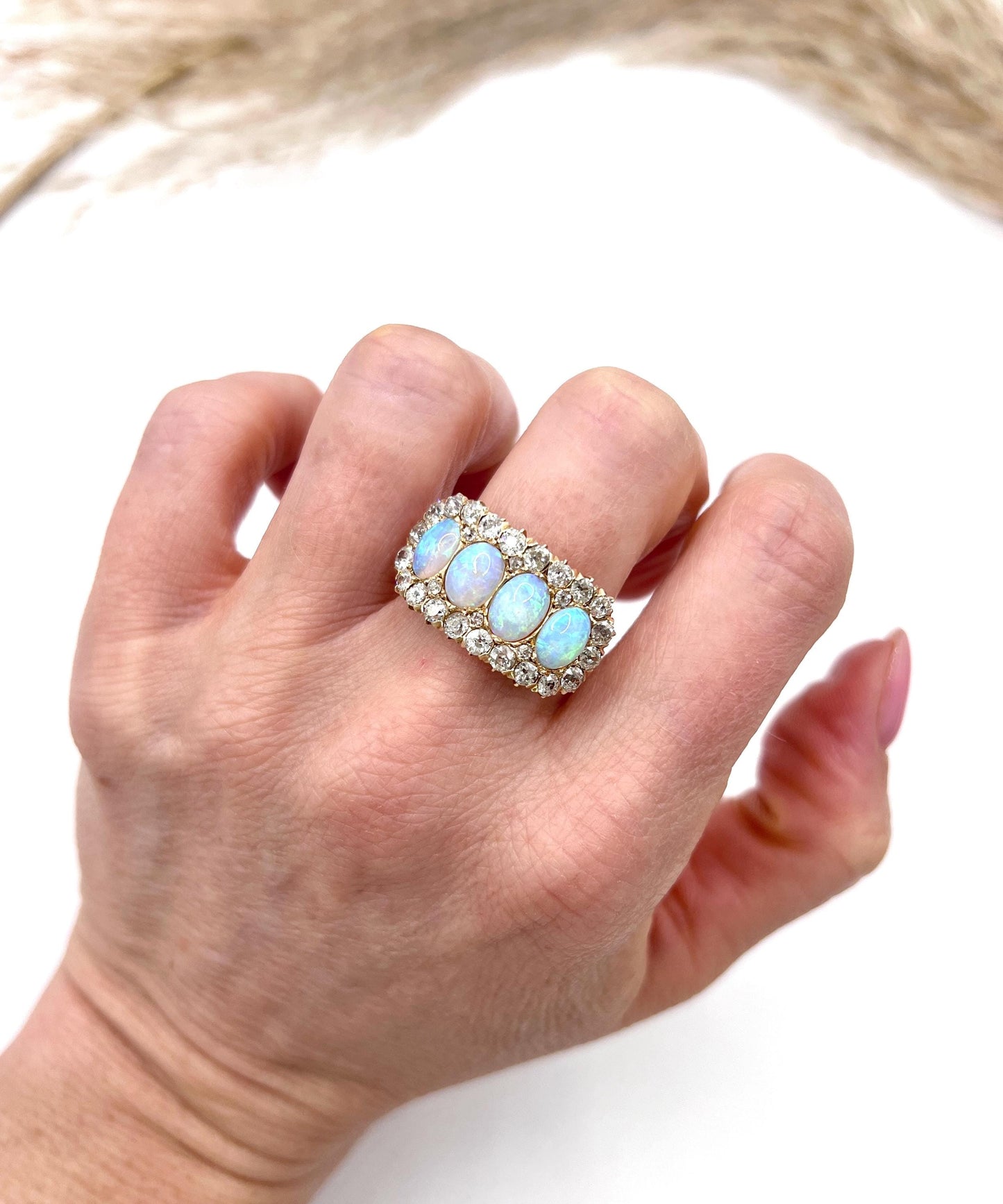 An antique oval opal and old cut diamond cluster row ring in yellow gold, modelled on a hand