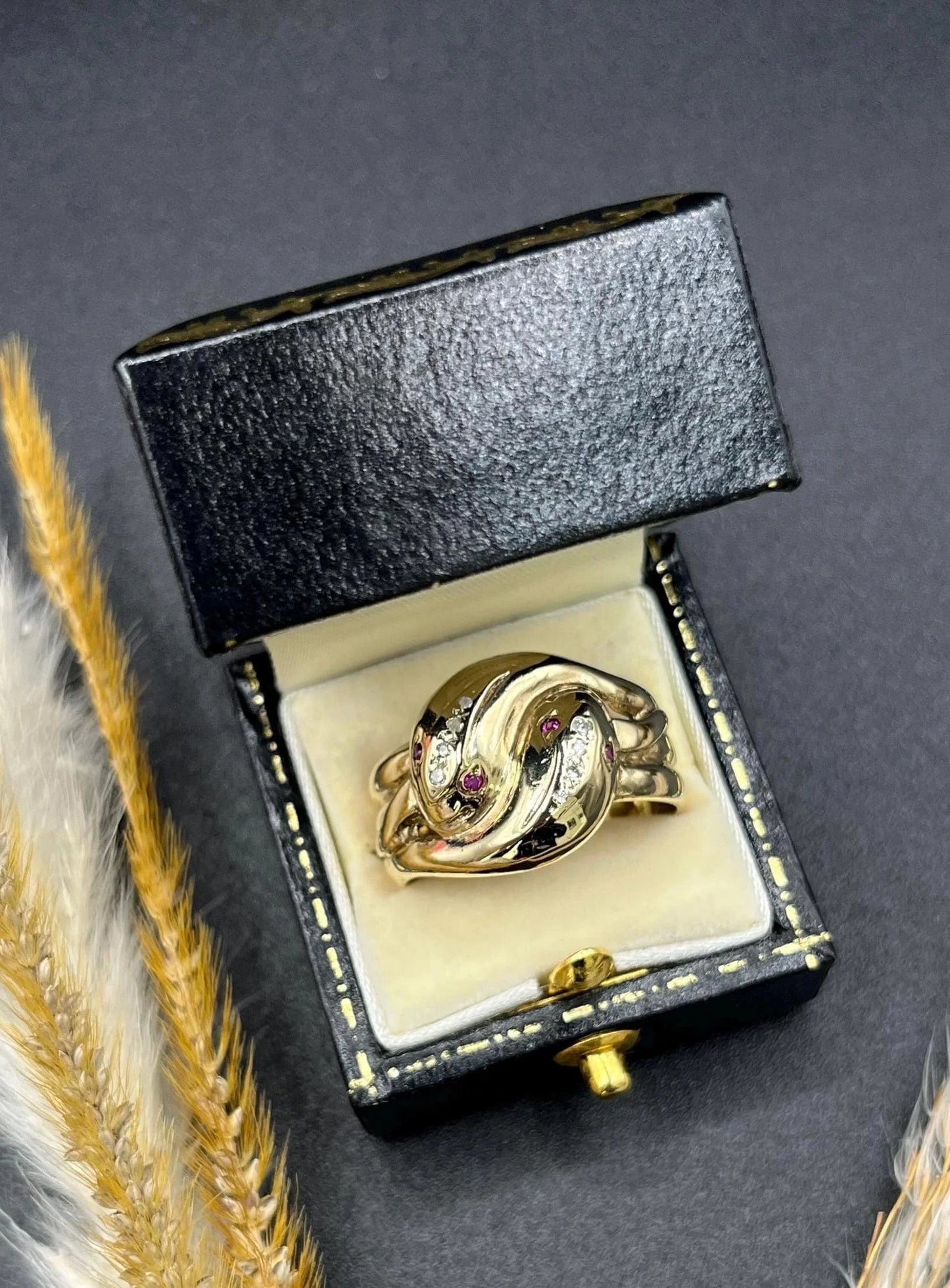 A yellow gold ruby and diamond set double headed snake ring, in a ring box