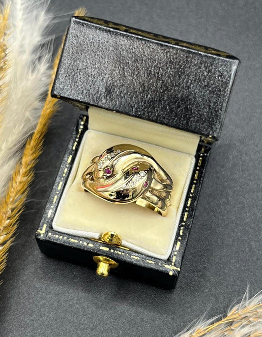 A yellow gold ruby and diamond set double headed snake ring, in a ring box