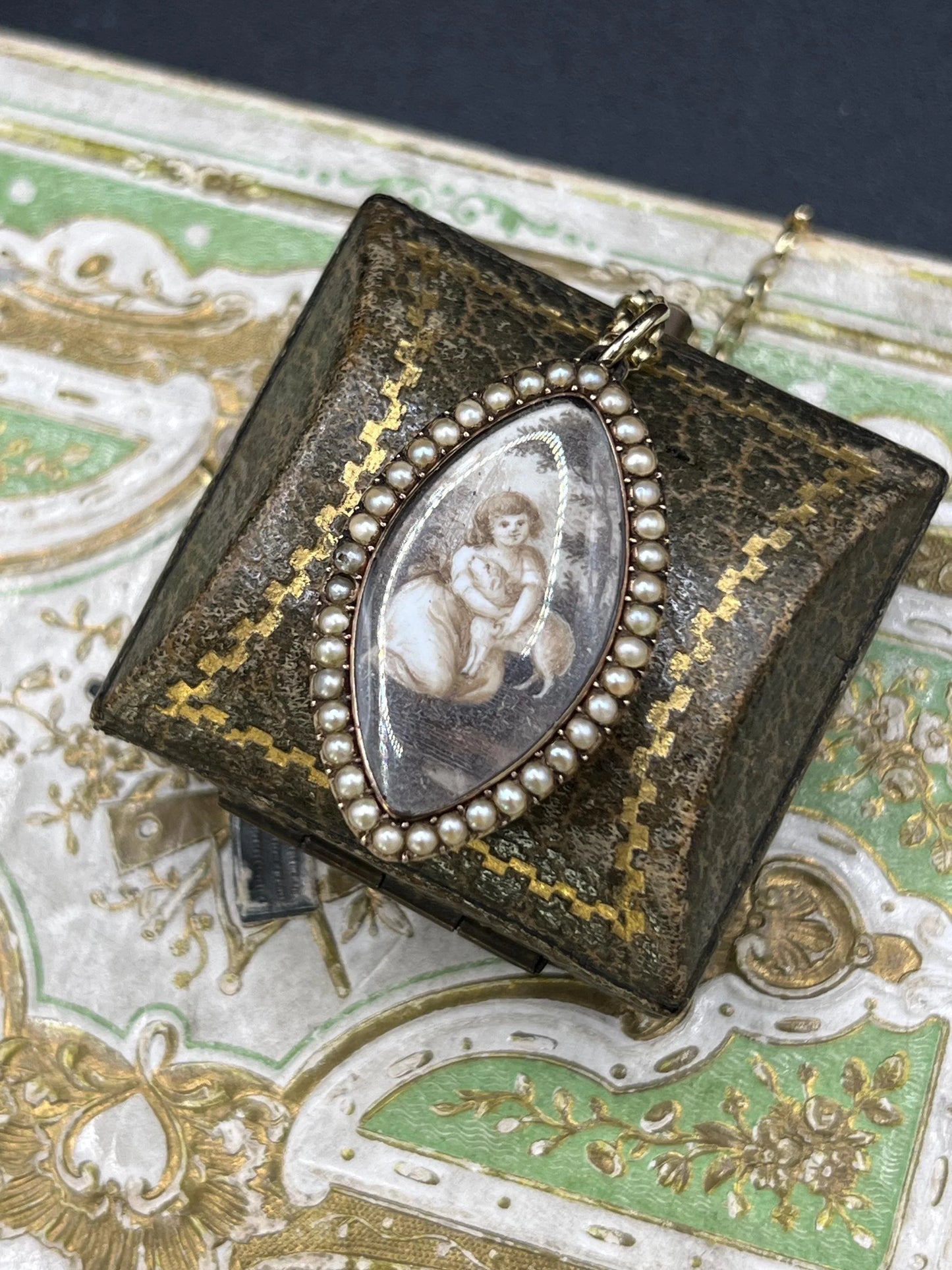 A navette shaped yellow gold seed pearl pendant with a miniature portrait, with a chain
