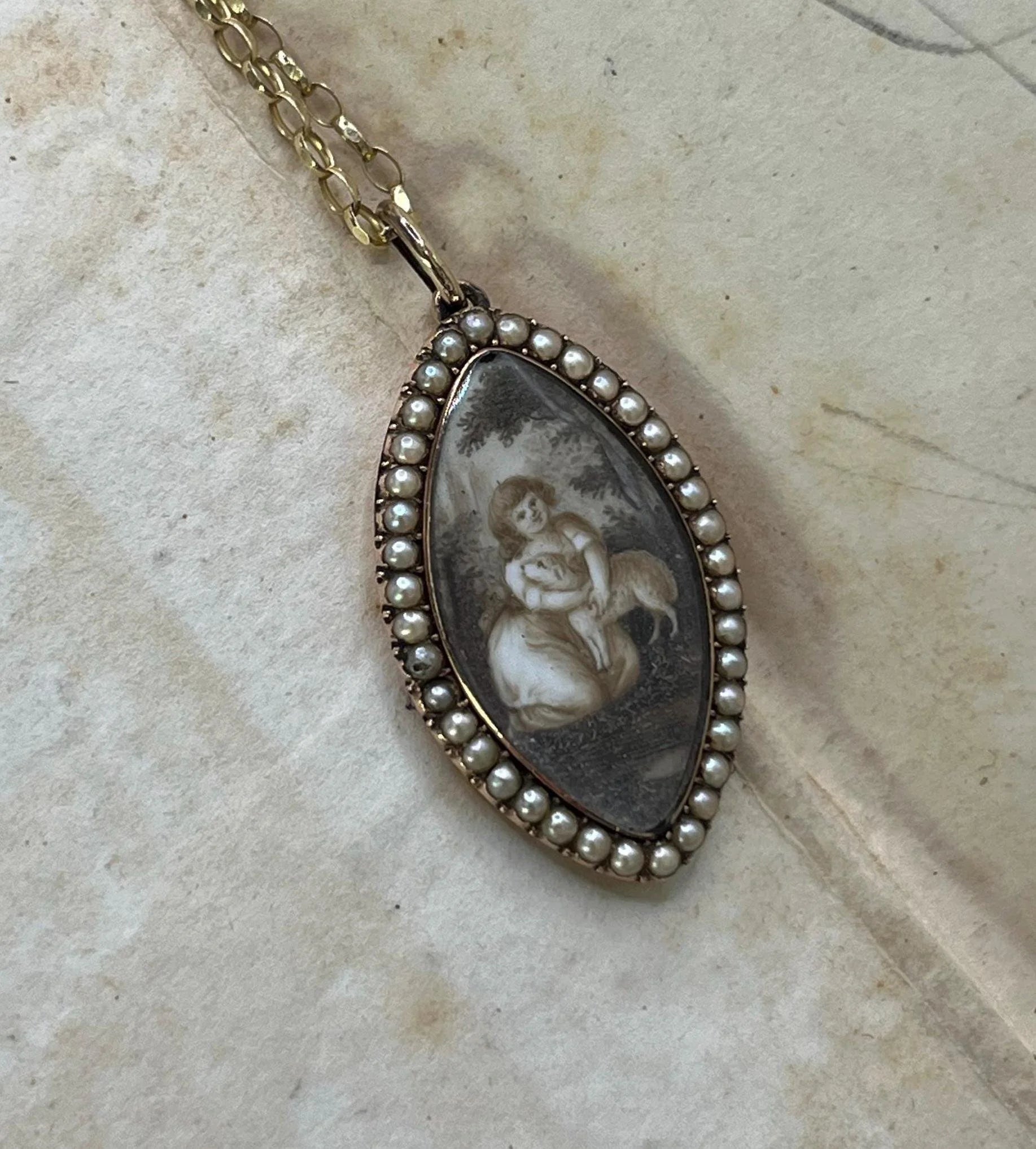 A navette shaped yellow gold seed pearl pendant with a miniature portrait, with a chain