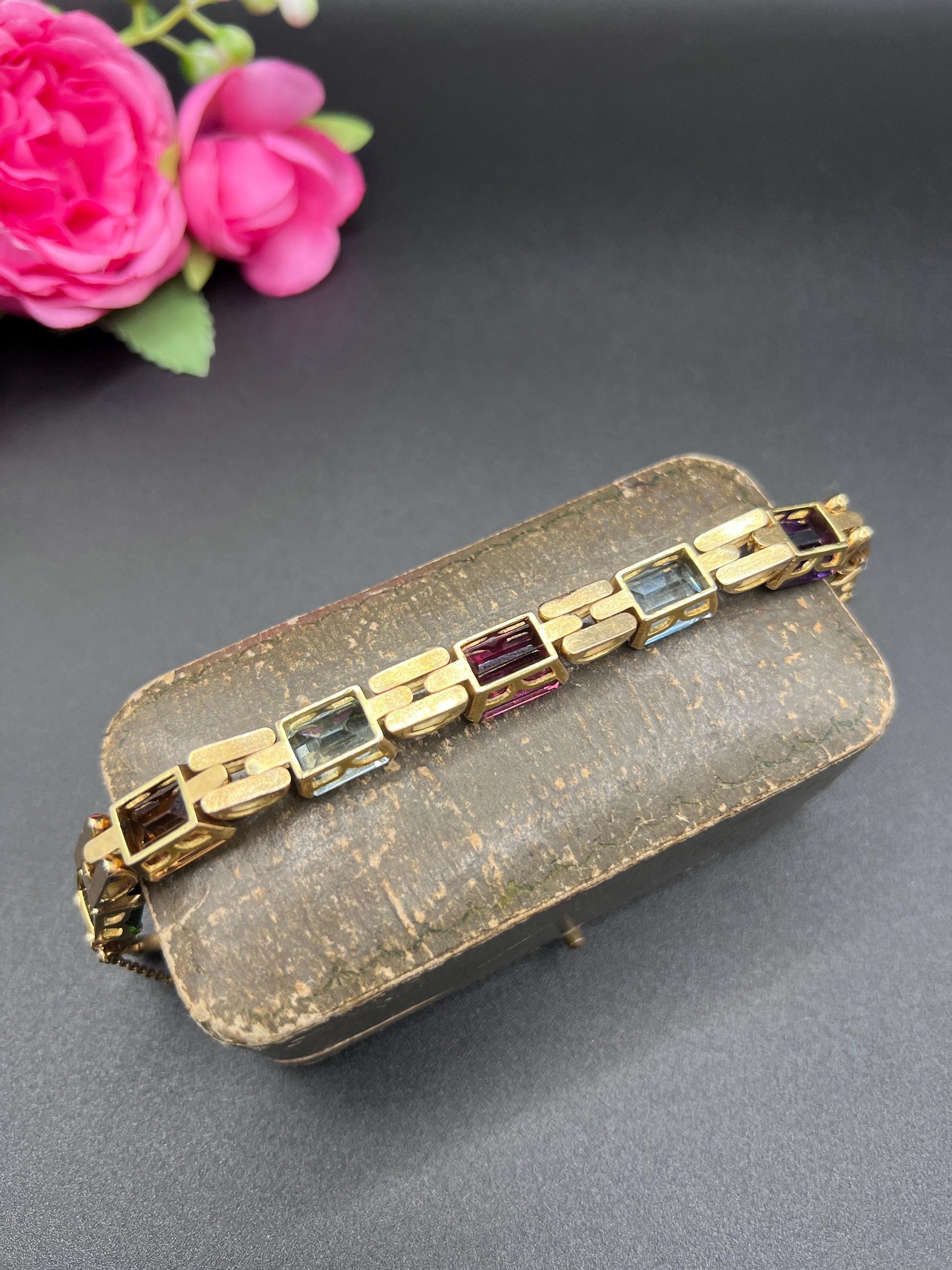 An emerald cut multi-gemstone bracelet in yellow gold