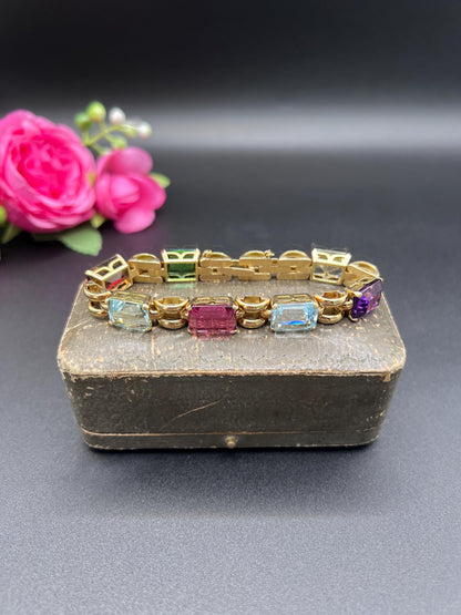 An emerald cut multi-gemstone bracelet in yellow gold