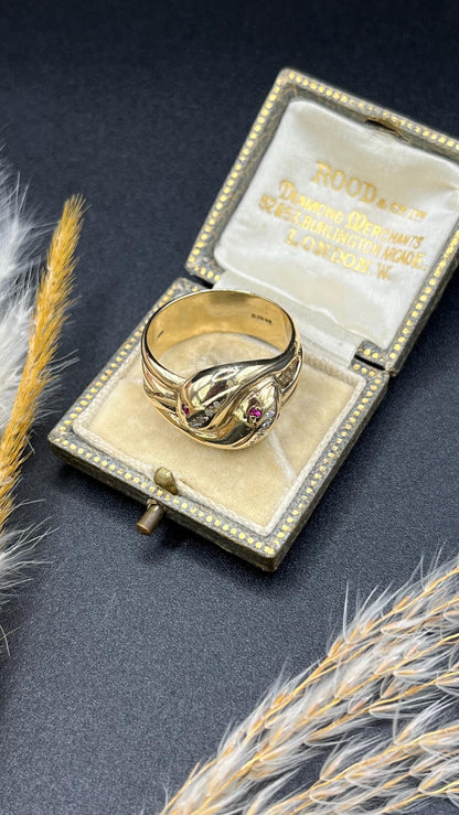 A yellow gold ruby and diamond set double headed snake ring, in a ring box