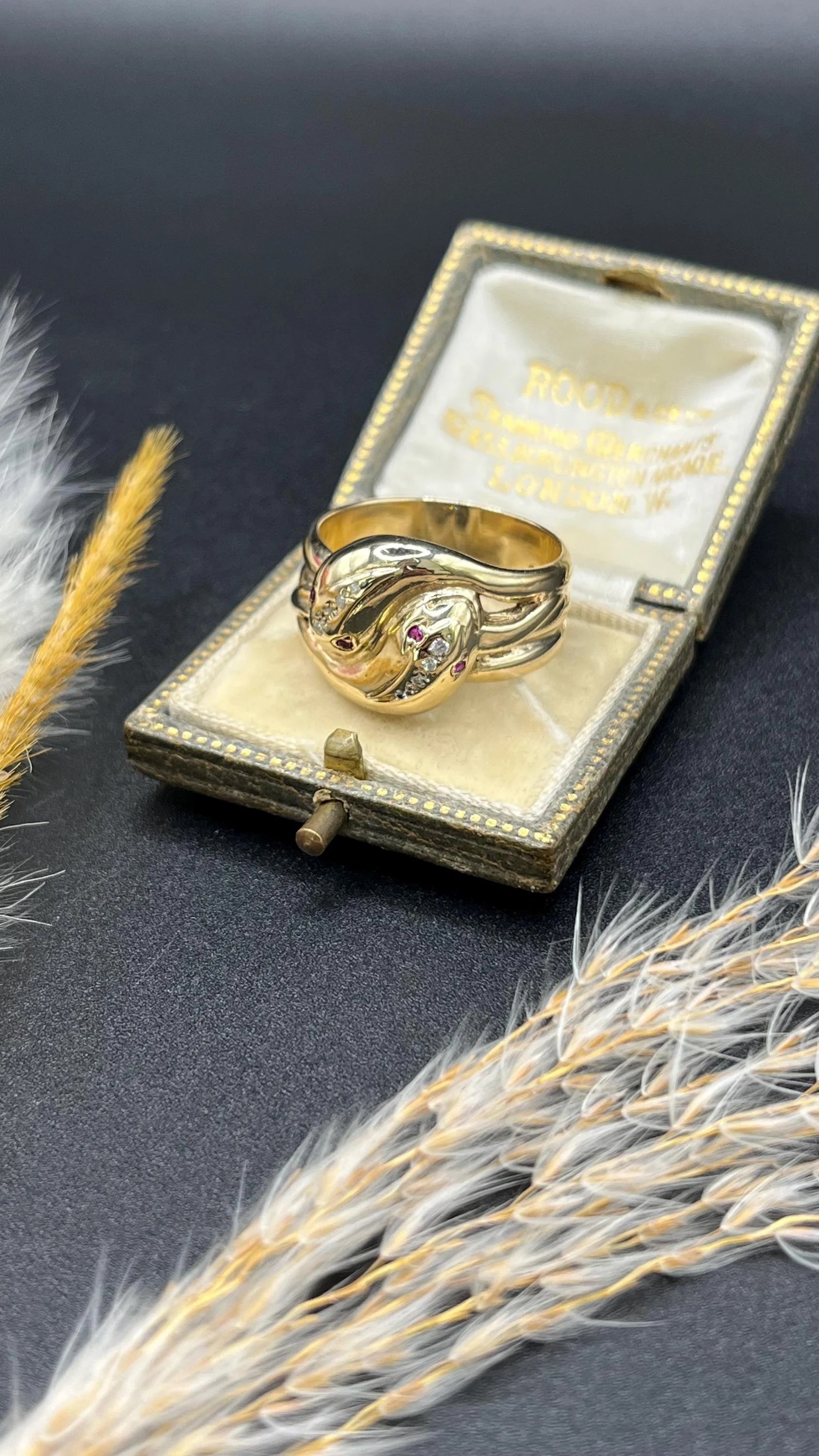A yellow gold ruby and diamond set double headed snake ring, in a ring box