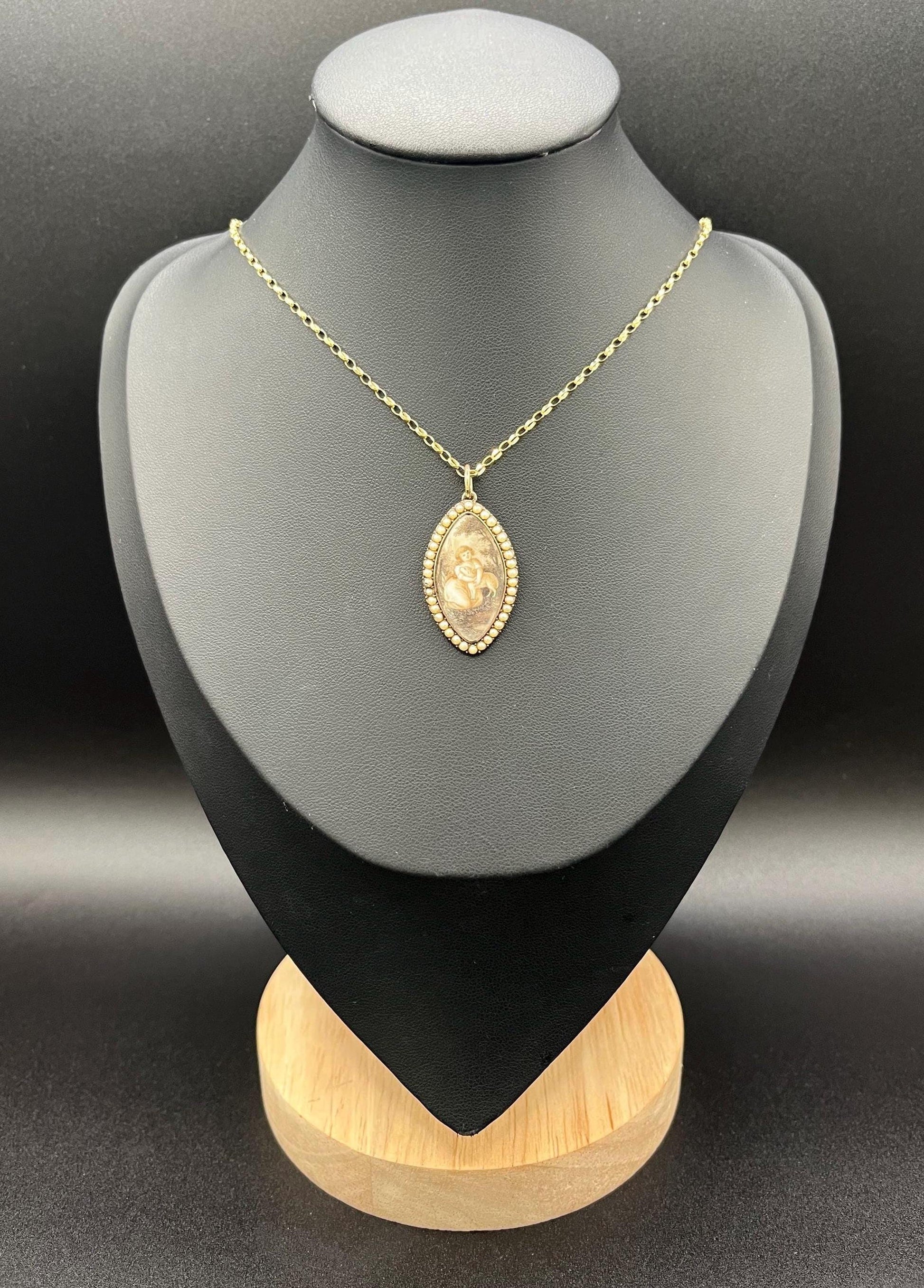 A navette shaped yellow gold seed pearl pendant with a miniature portrait, with a chain, on a black jewellery bust