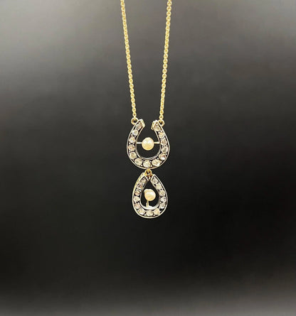 A pearl and diamond set doube horseshoe pendant on a gold chain