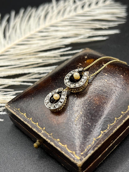 A pearl and diamond set doube horseshoe pendant on a gold chain