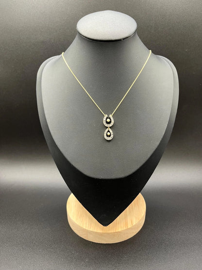 A pearl and diamond set doube horseshoe pendant on a gold chain