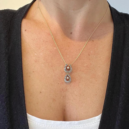 A pearl and diamond set doube horseshoe pendant on a gold chain, modelled by a woman