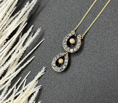 A pearl and diamond set doube horseshoe pendant on a gold chain