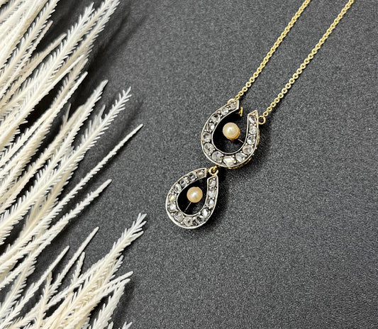 A pearl and diamond set doube horseshoe pendant on a gold chain