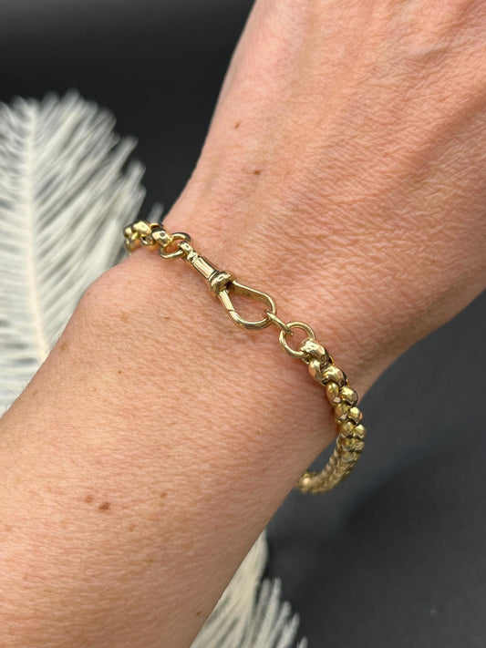 A yellow gold round link bracelet with a lobster claw clasp, modelled on a wrist