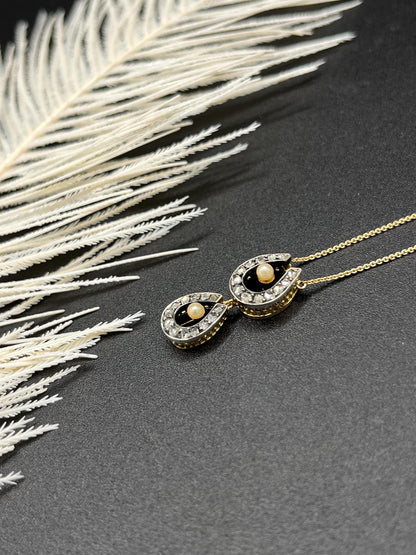 A pearl and diamond set doube horseshoe pendant on a gold chain