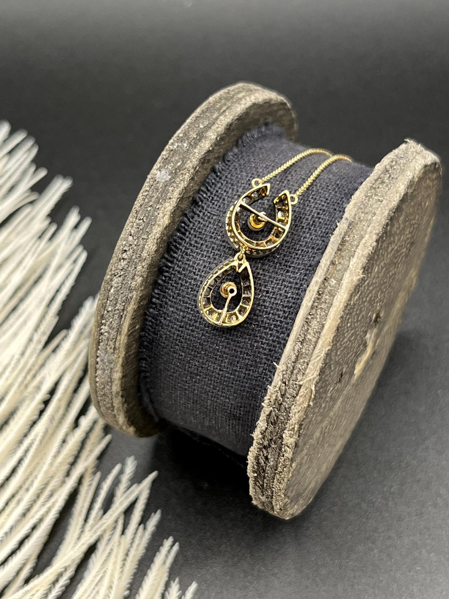 A pearl and diamond set doube horseshoe pendant on a gold chain