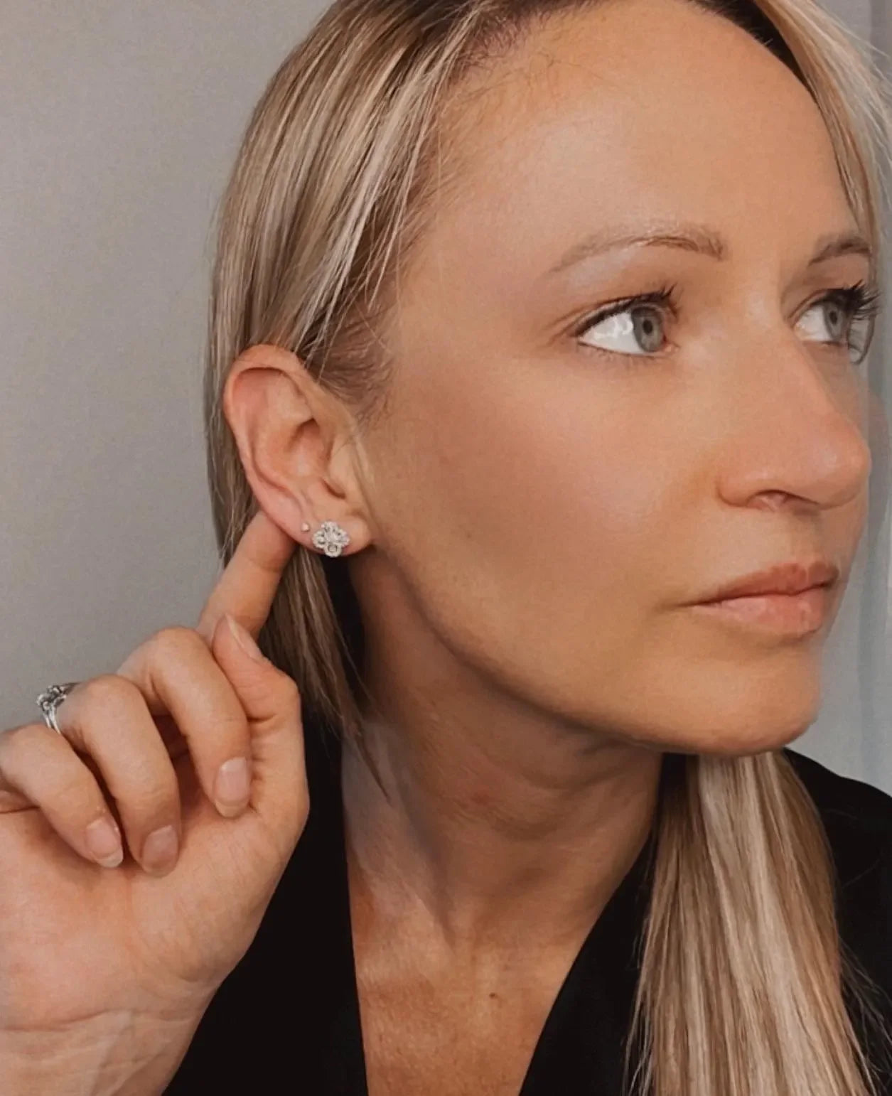 A white gold clover shaped diamond cluster stud earring, modelled in an ear