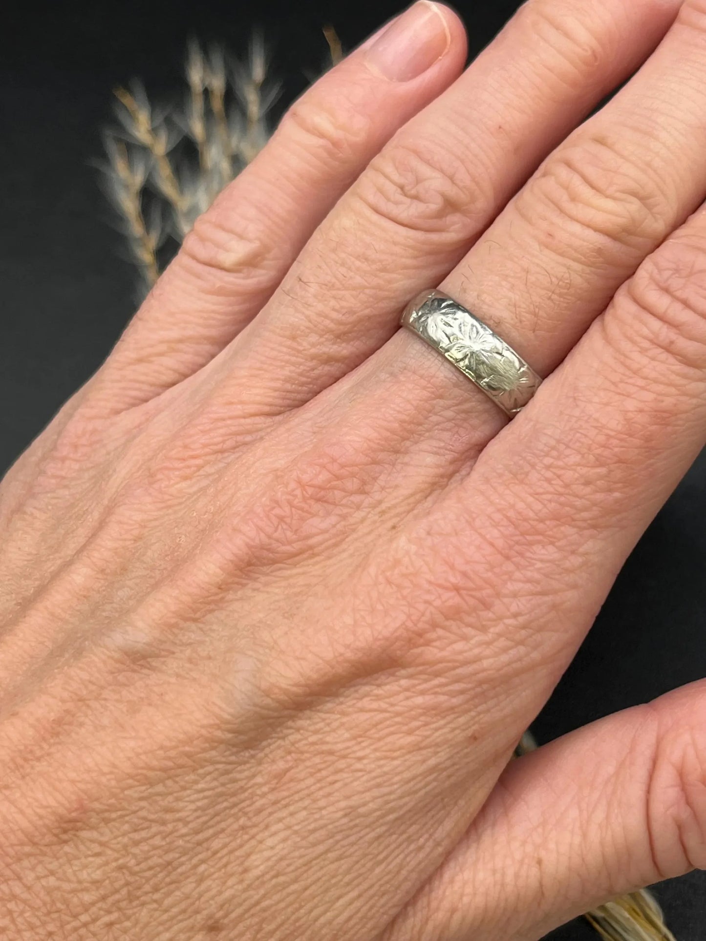 An engraved platinum wedding band ring, modelled on a hand