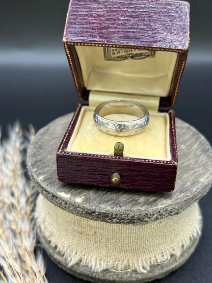An engraved platinum wedding band ring, in an antique ring box
