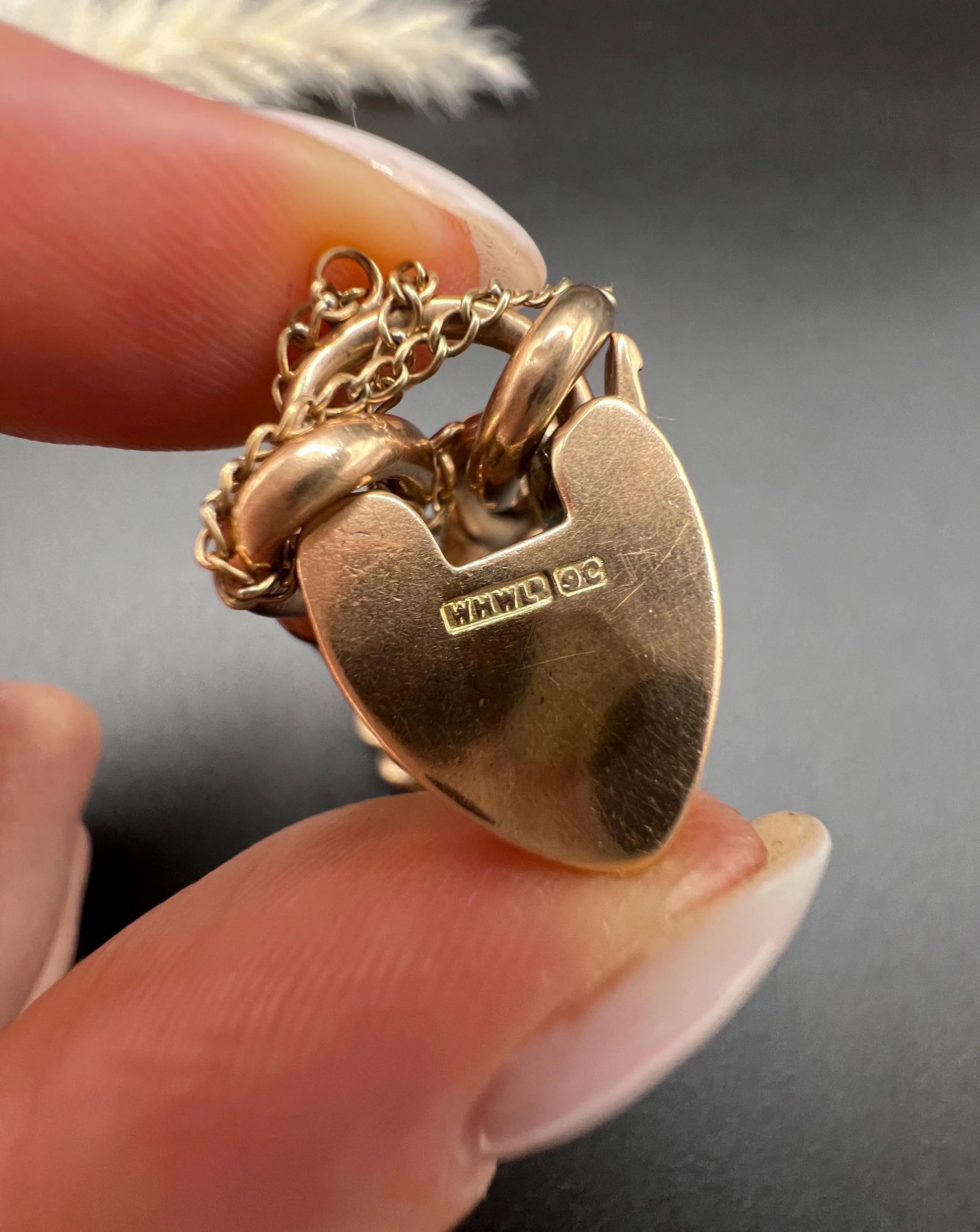 Close-up of stamps on a gold heart shaped padlock clasp