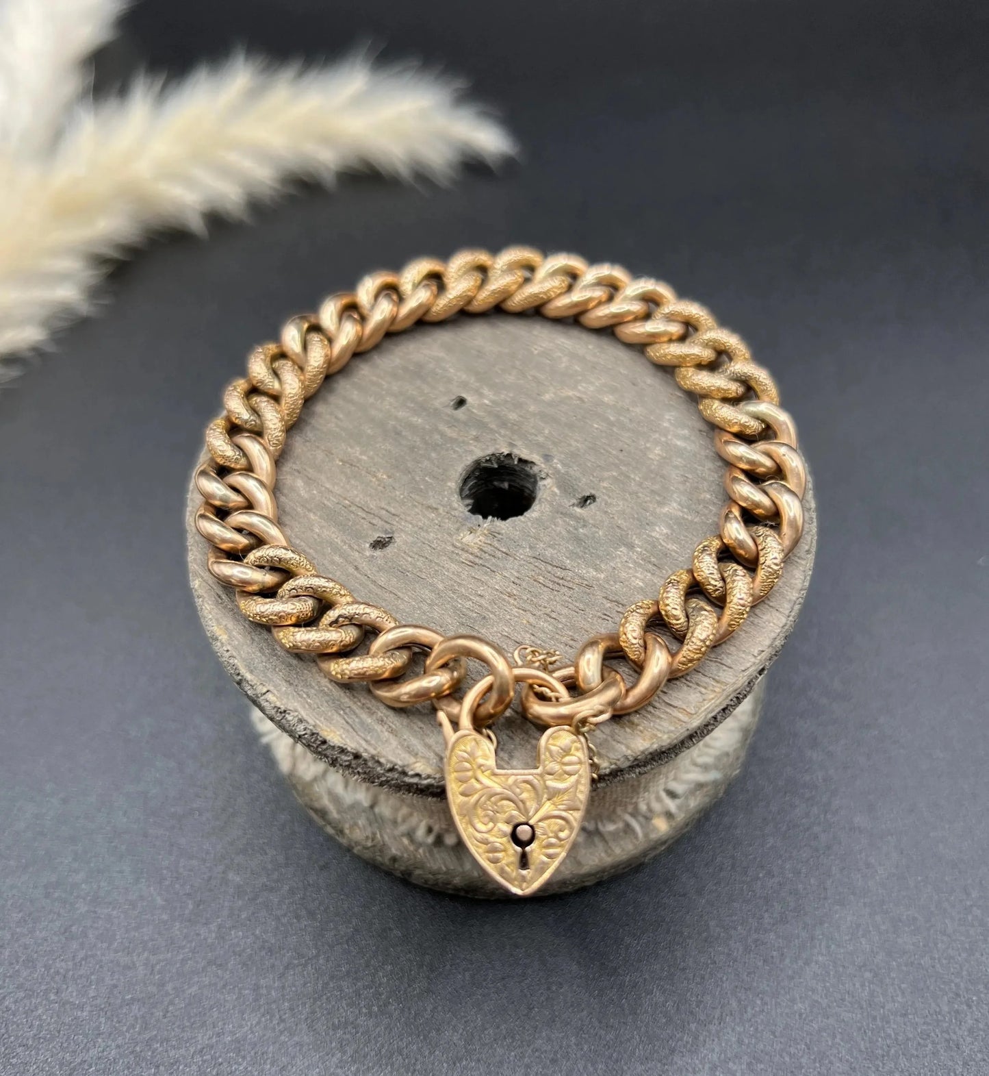 A rose gold curb link bracelet with engraved heart padlock clasp
