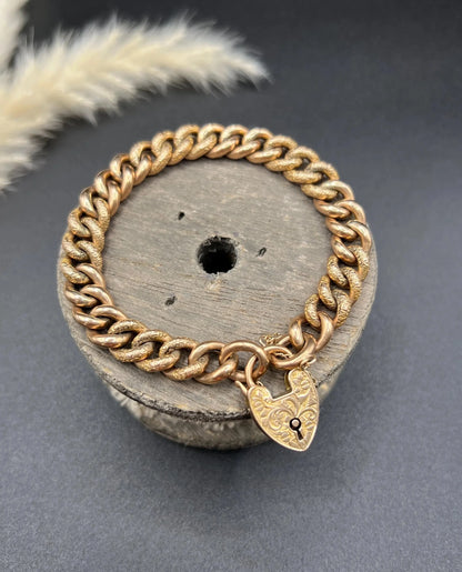A rose gold curb link bracelet with engraved heart padlock clasp
