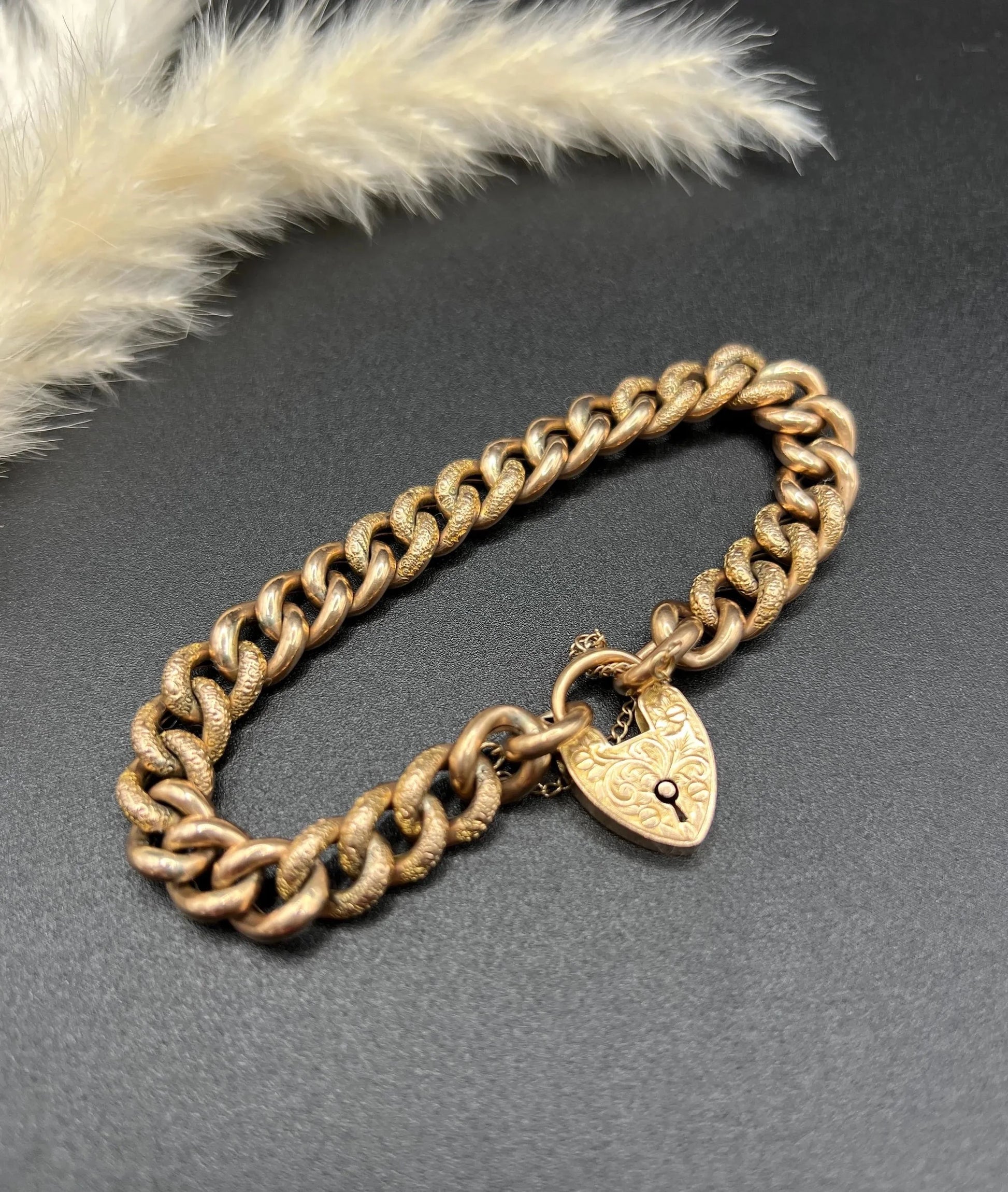 A rose gold curb link bracelet with engraved heart padlock clasp