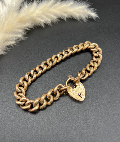 A rose gold curb link bracelet with engraved heart padlock clasp