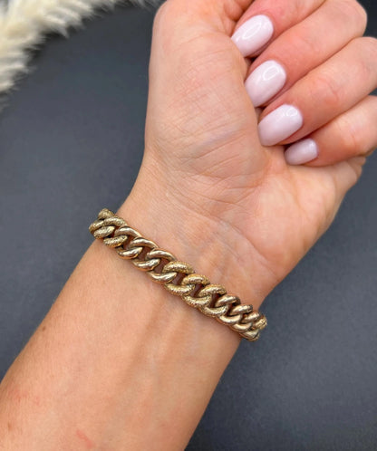 A rose gold curb link bracelet modelled on a wrist