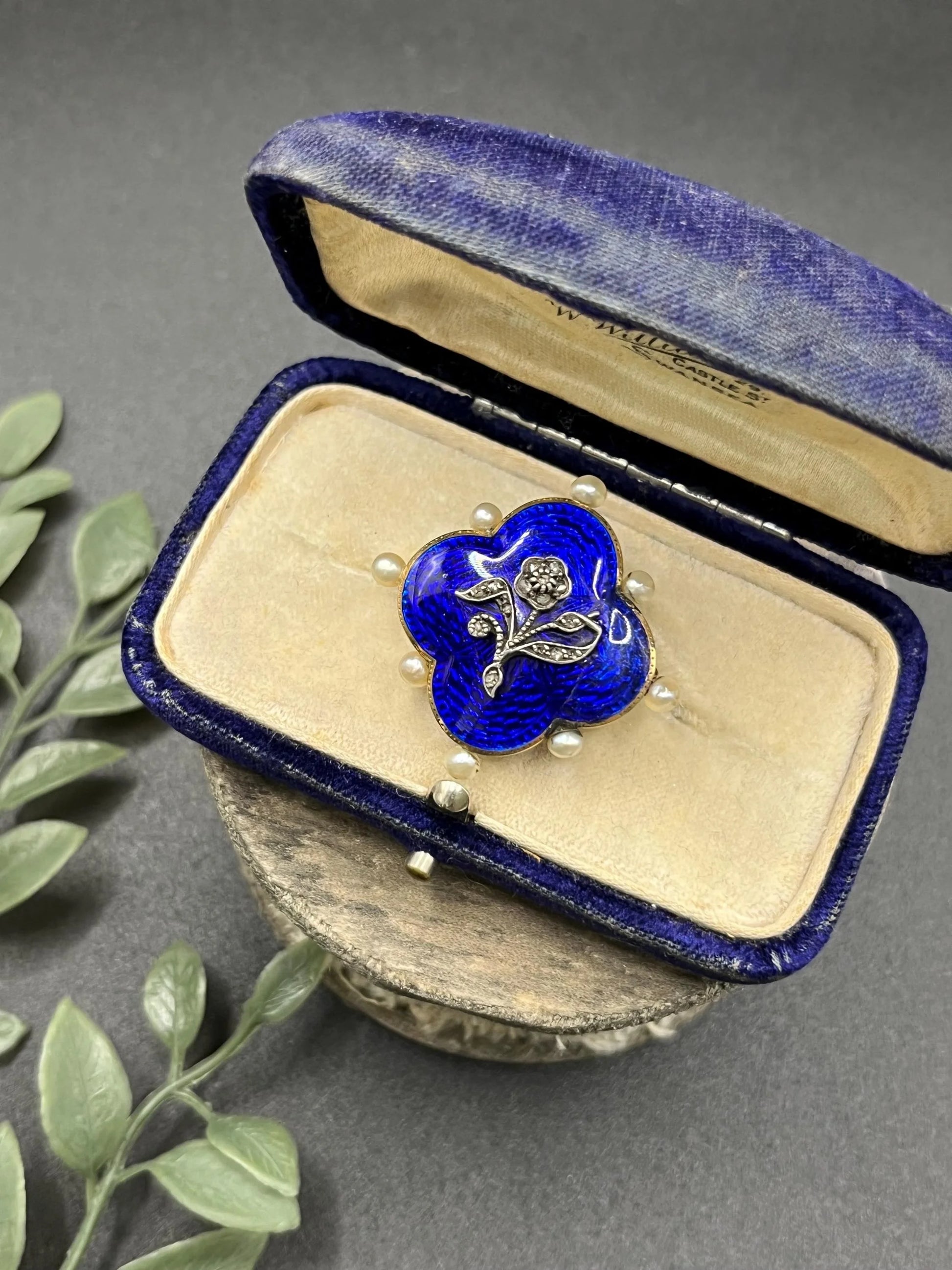 A diamond flower, blue enamel and pearl brooch in yellow gold, in an antique box