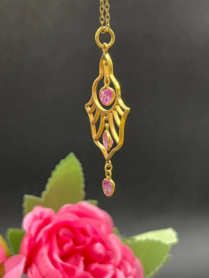 A yellow gold three stone ruby openwork drop pendant on a yellow gold chain