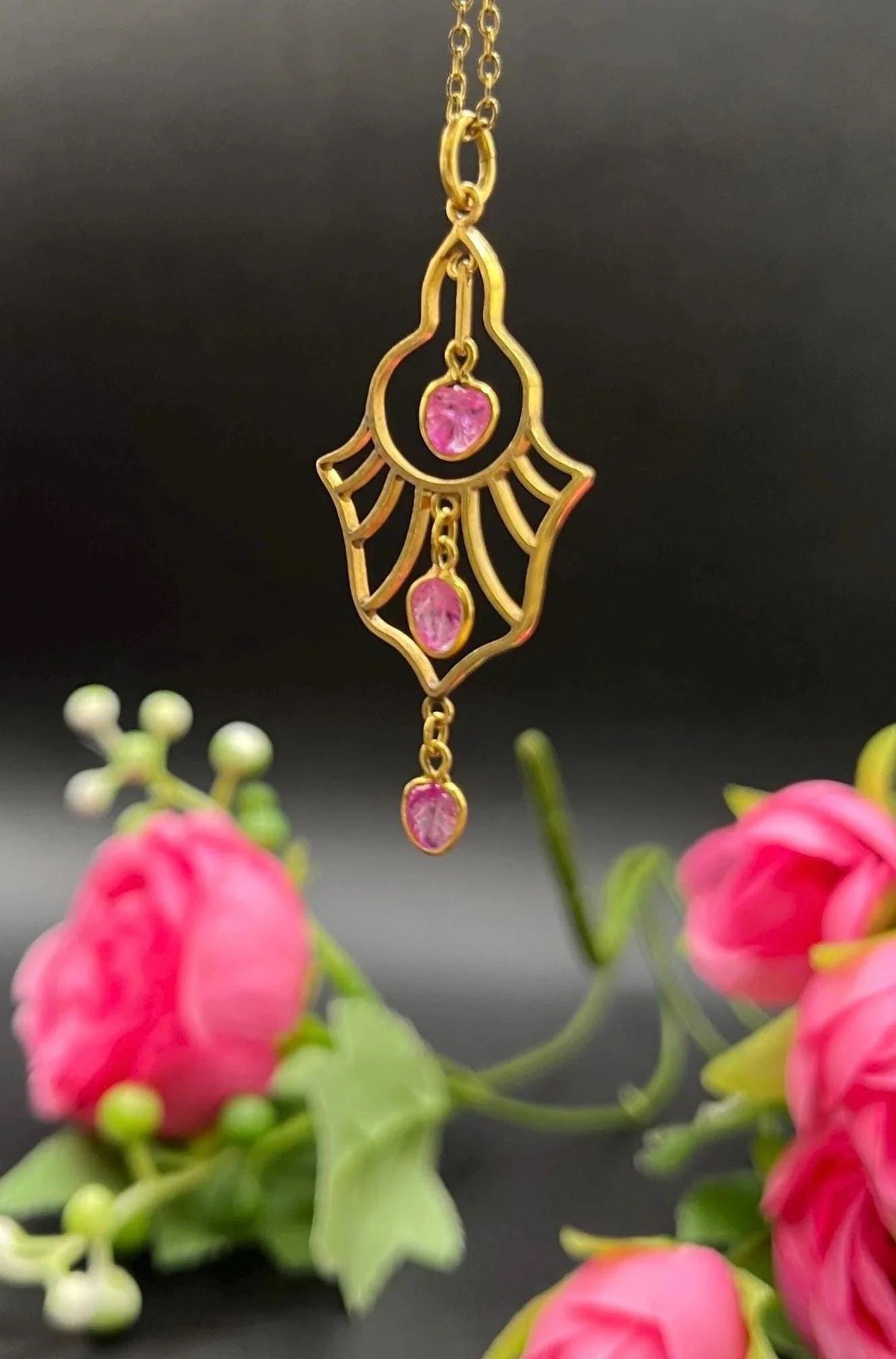 A yellow gold three stone ruby openwork drop pendant on a yellow gold chain