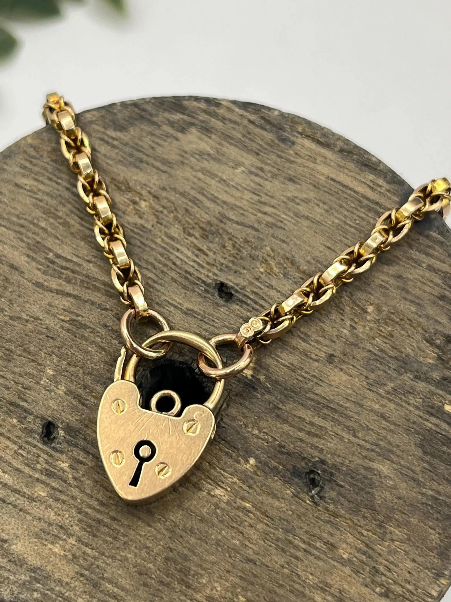 A yellow gold chain necklace with a heart shaped padlock clasp