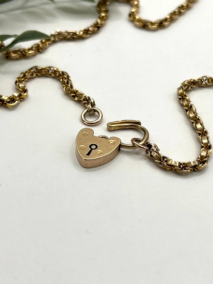 A yellow gold chain necklace with a heart shaped padlock clasp