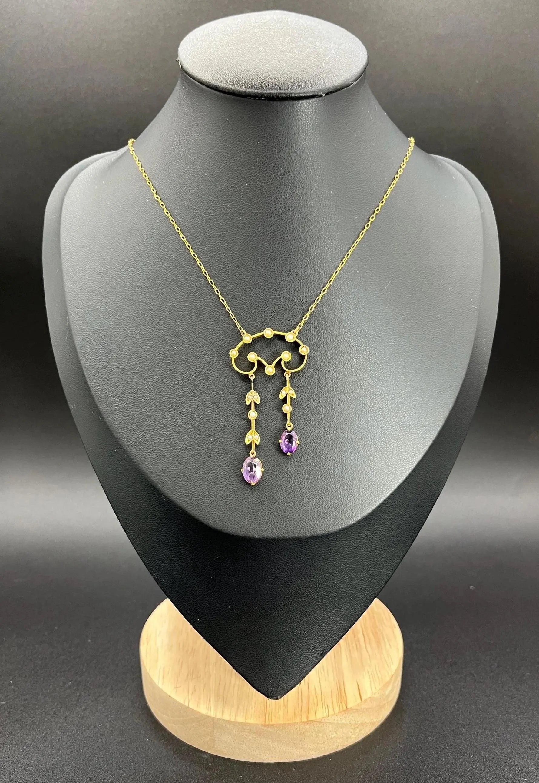 An amethyst and seed pearl drop pendant necklace in yellow gold, on a black jewellery bust
