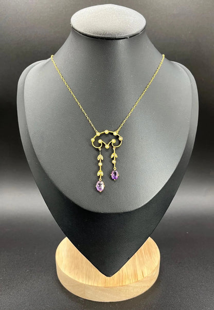 An amethyst and seed pearl drop pendant necklace in yellow gold, on a black jewellery bust