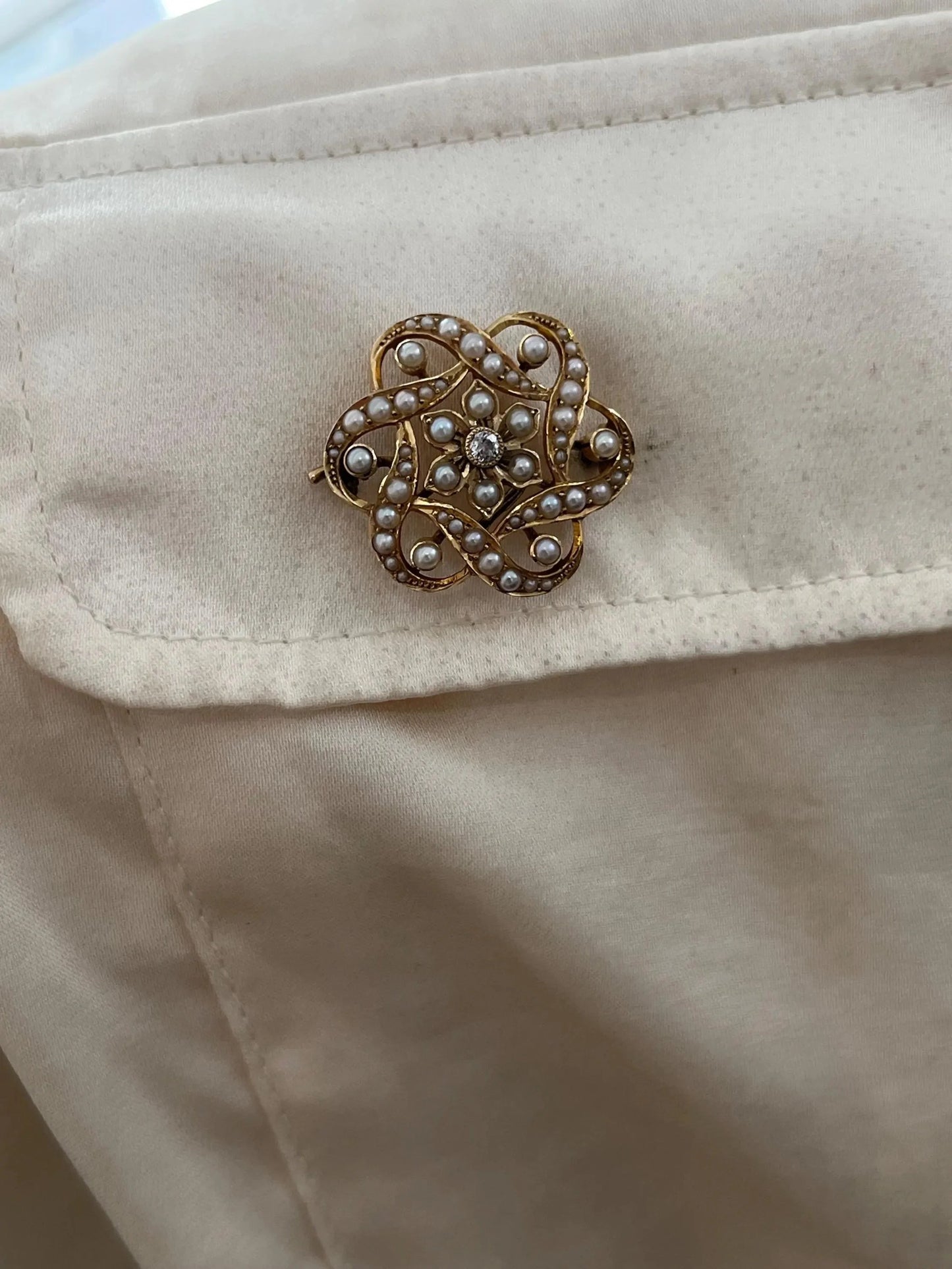 A yellow gold seed pearl and diamond floral brooch/pendant, modelled on a white shirt