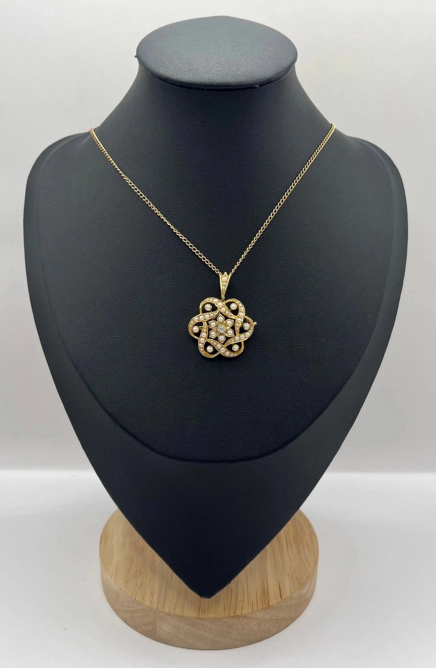 A yellow gold seed pearl and diamond floral brooch/pendant, with a chain, modelled on a black jewellery bust