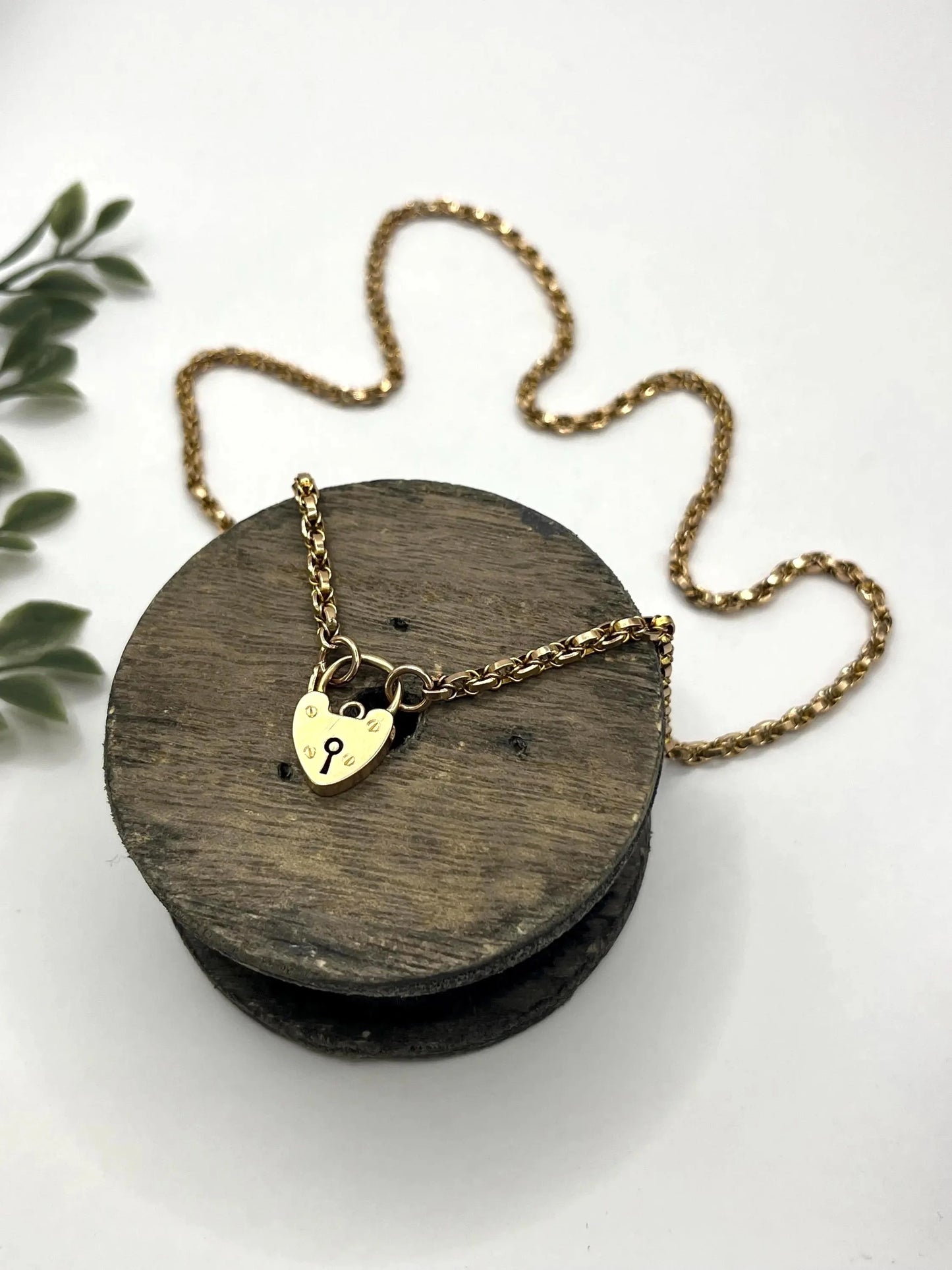 A yellow gold chain necklace with a heart shaped padlock clasp
