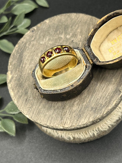 A yellow gold four stone garnet band ring, in an antique ring box