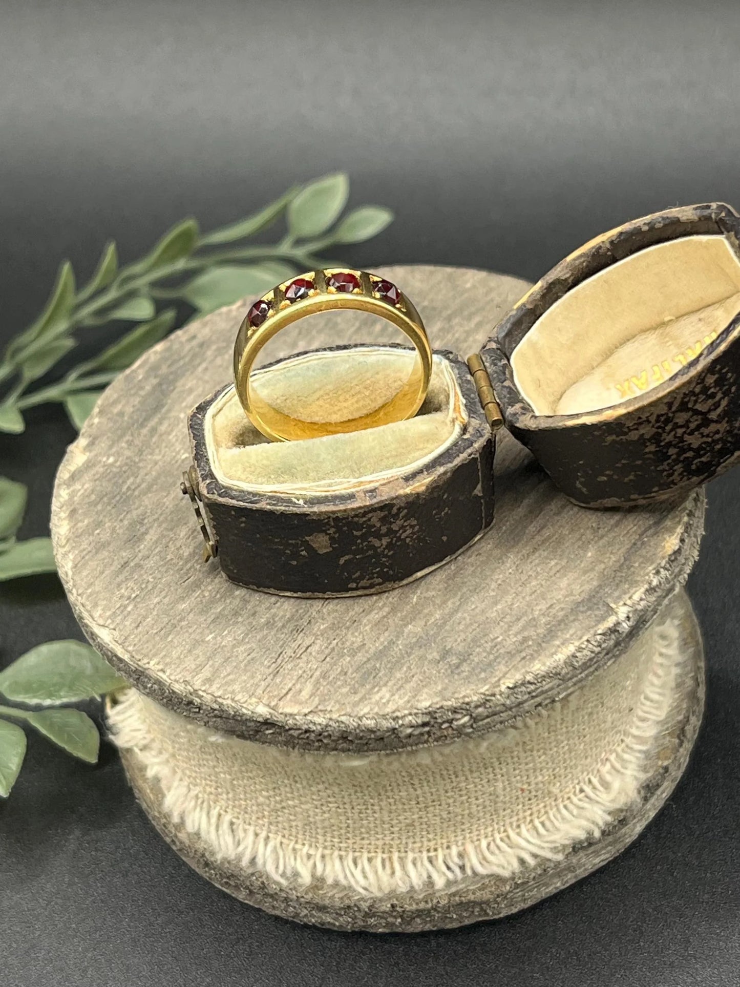 A yellow gold four stone garnet band ring, in an antique ring box