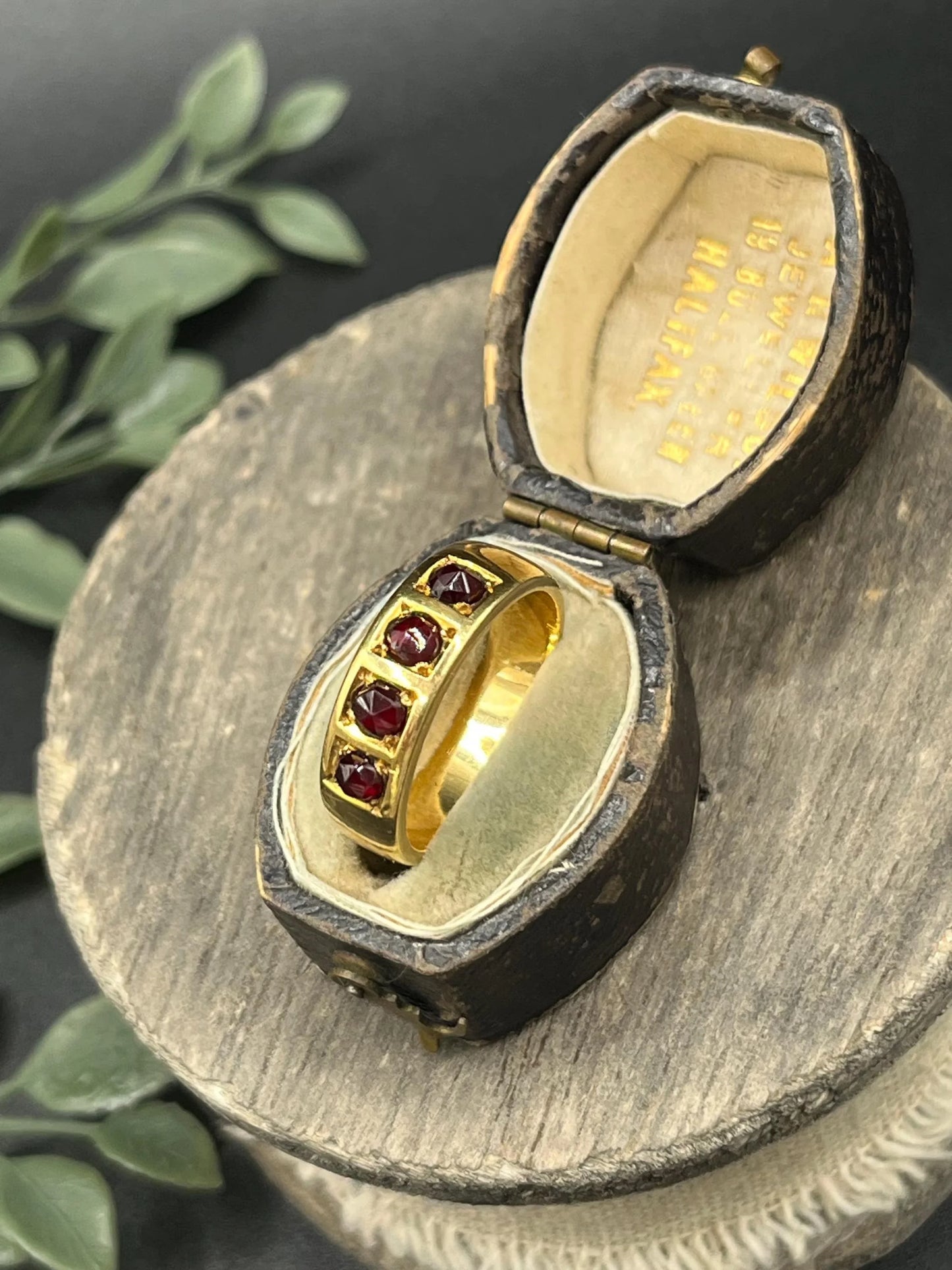 A yellow gold four stone garnet band ring, in an antique ring box