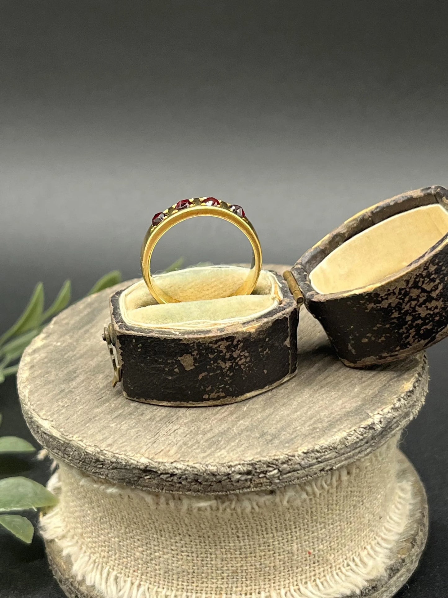 A yellow gold four stone garnet band ring, in an antique ring box