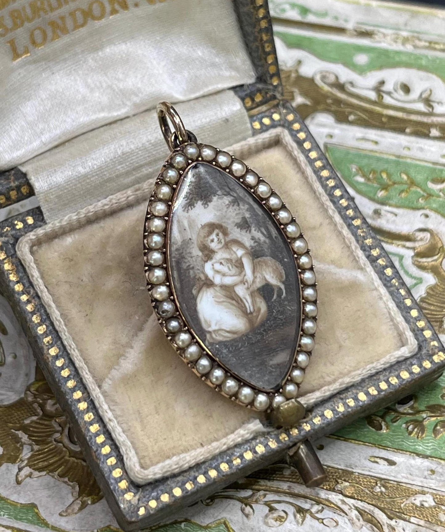 A navette shaped yellow gold seed pearl pendant with a miniature portrait, in an antique box
