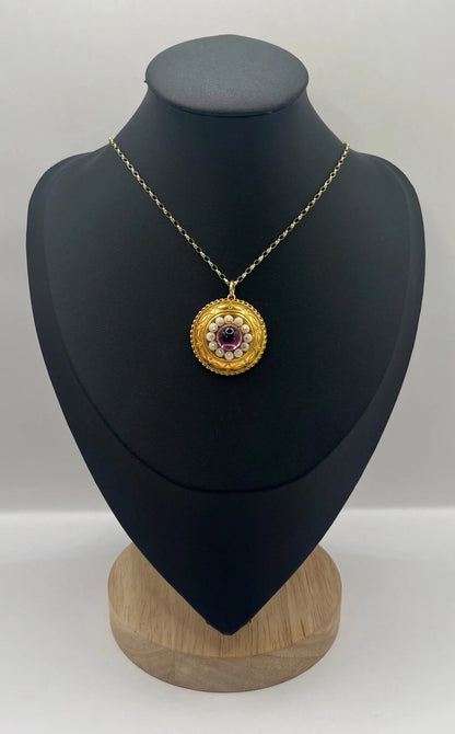 A round etruscan style pendant with a cabochon amethyst and carved coral in yellow gold, with a gold chain