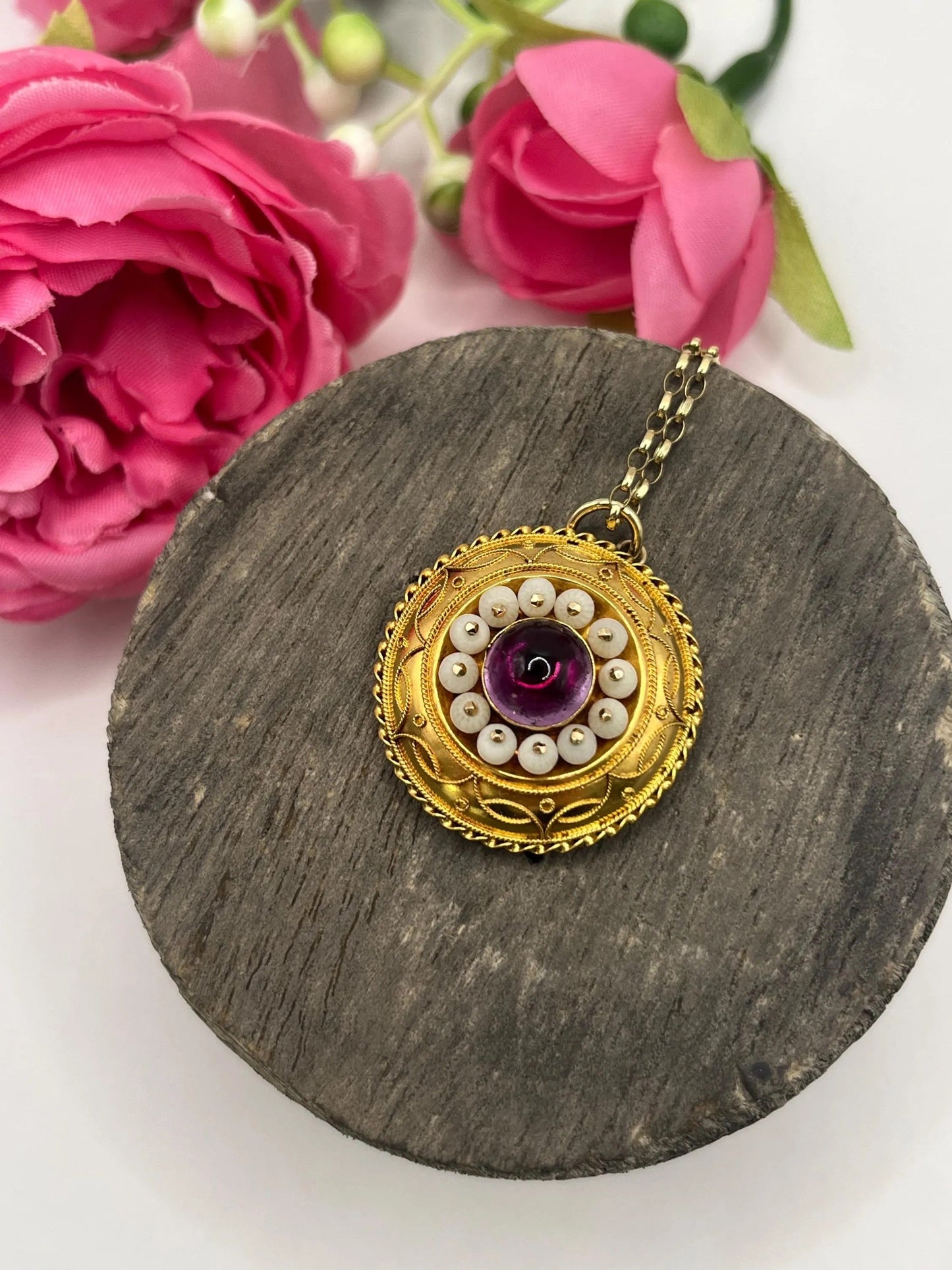 A round etruscan style pendant with a cabochon amethyst and carved coral in yellow gold, with a gold chain