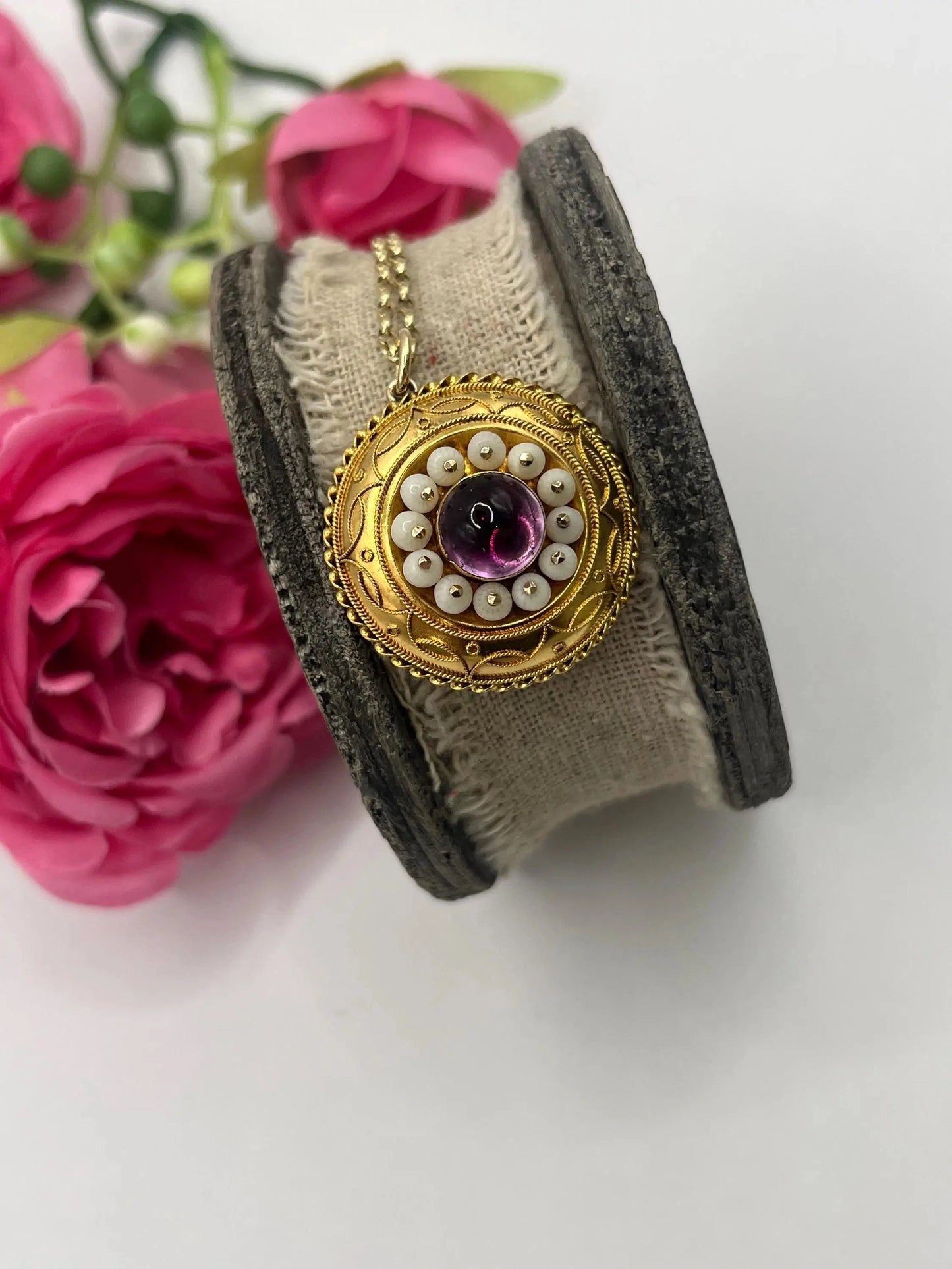 A round etruscan style pendant with a cabochon amethyst and carved coral in yellow gold, with a gold chain