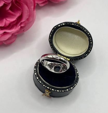 A cabochon sapphire and round diamond three stone band ring in white gold