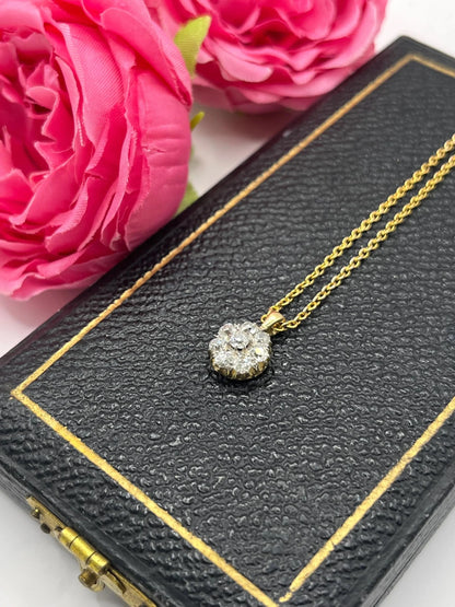 A diamond cluster pendant in yellow and white gold with a yellow gold chain