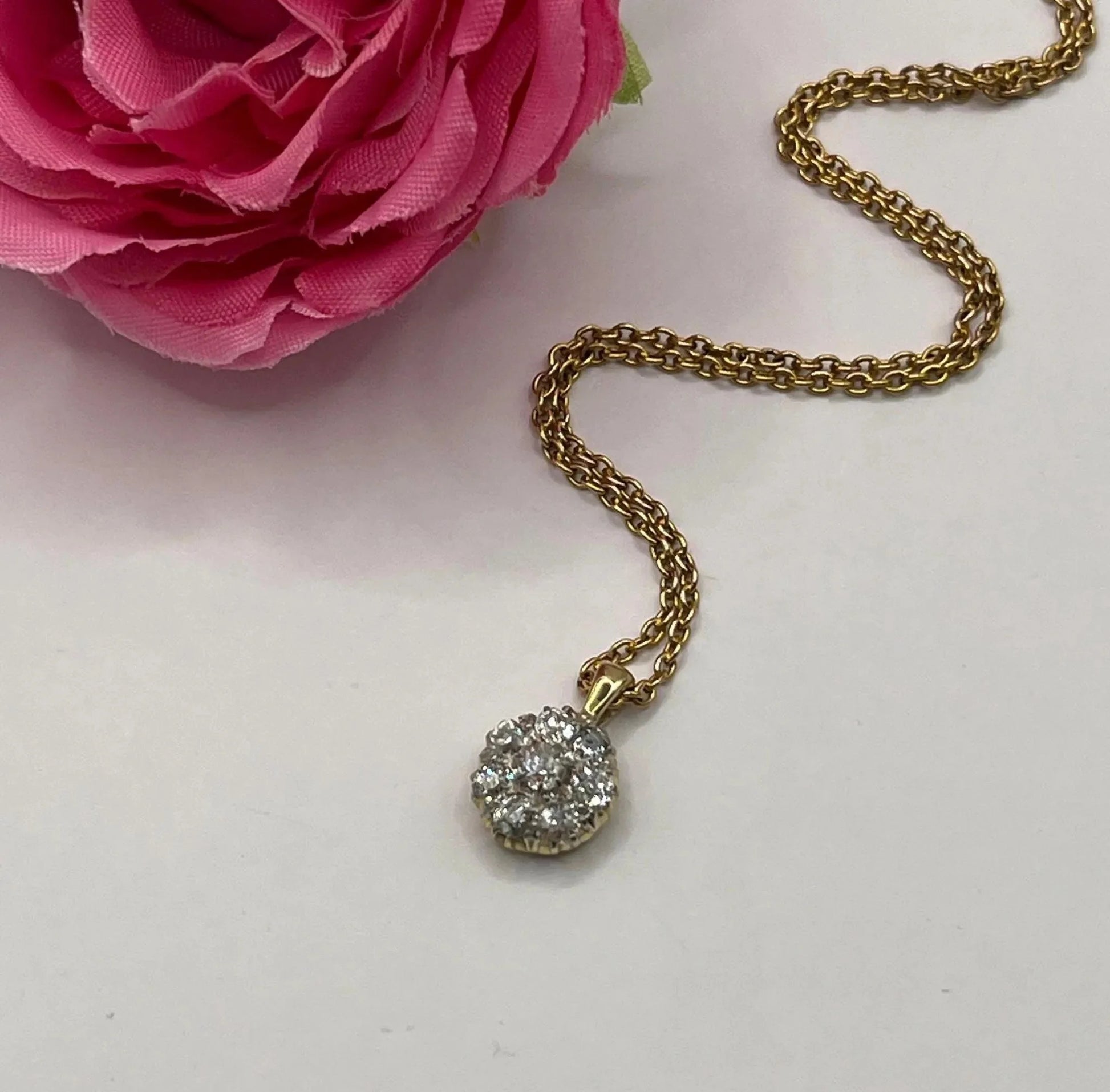 A diamond cluster pendant in yellow and white gold with a yellow gold chain
