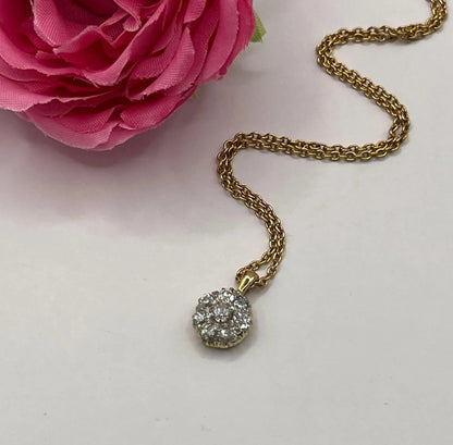 A diamond cluster pendant in yellow and white gold with a yellow gold chain